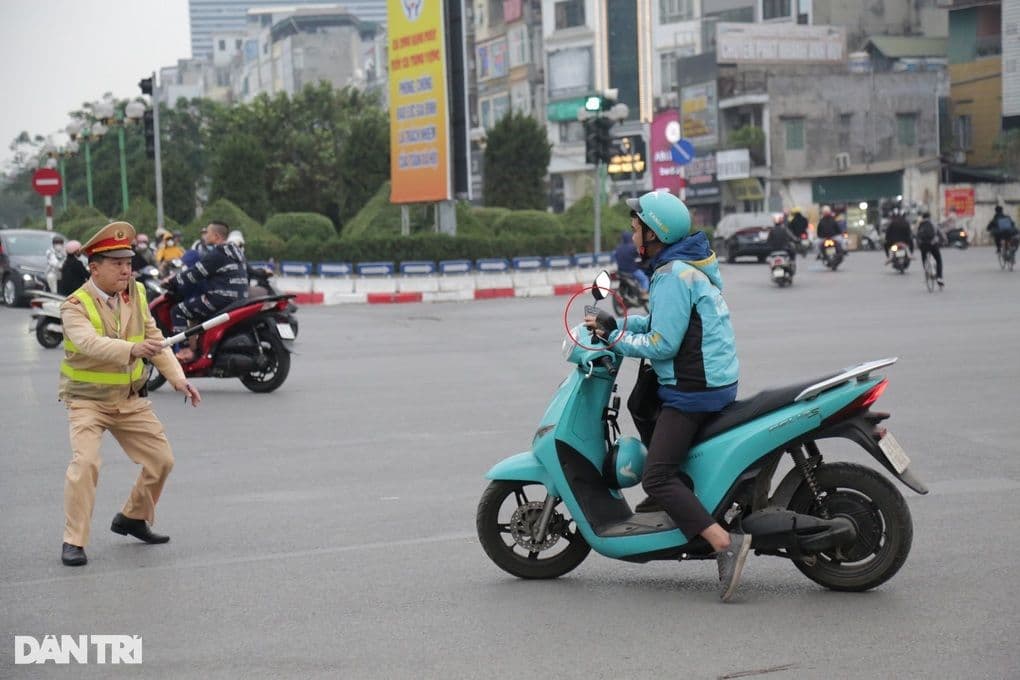 Cảnh sát giao thông hướng dẫn người điều khiển xe máy tại ngã tư, thể hiện vai trò phục vụ nhân dân.