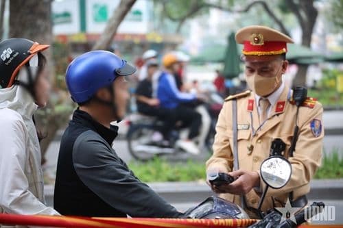 Cảnh sát giao thông kiểm tra giấy tờ người điều khiển xe máy, thể hiện vai trò của con người trong an toàn giao thông.