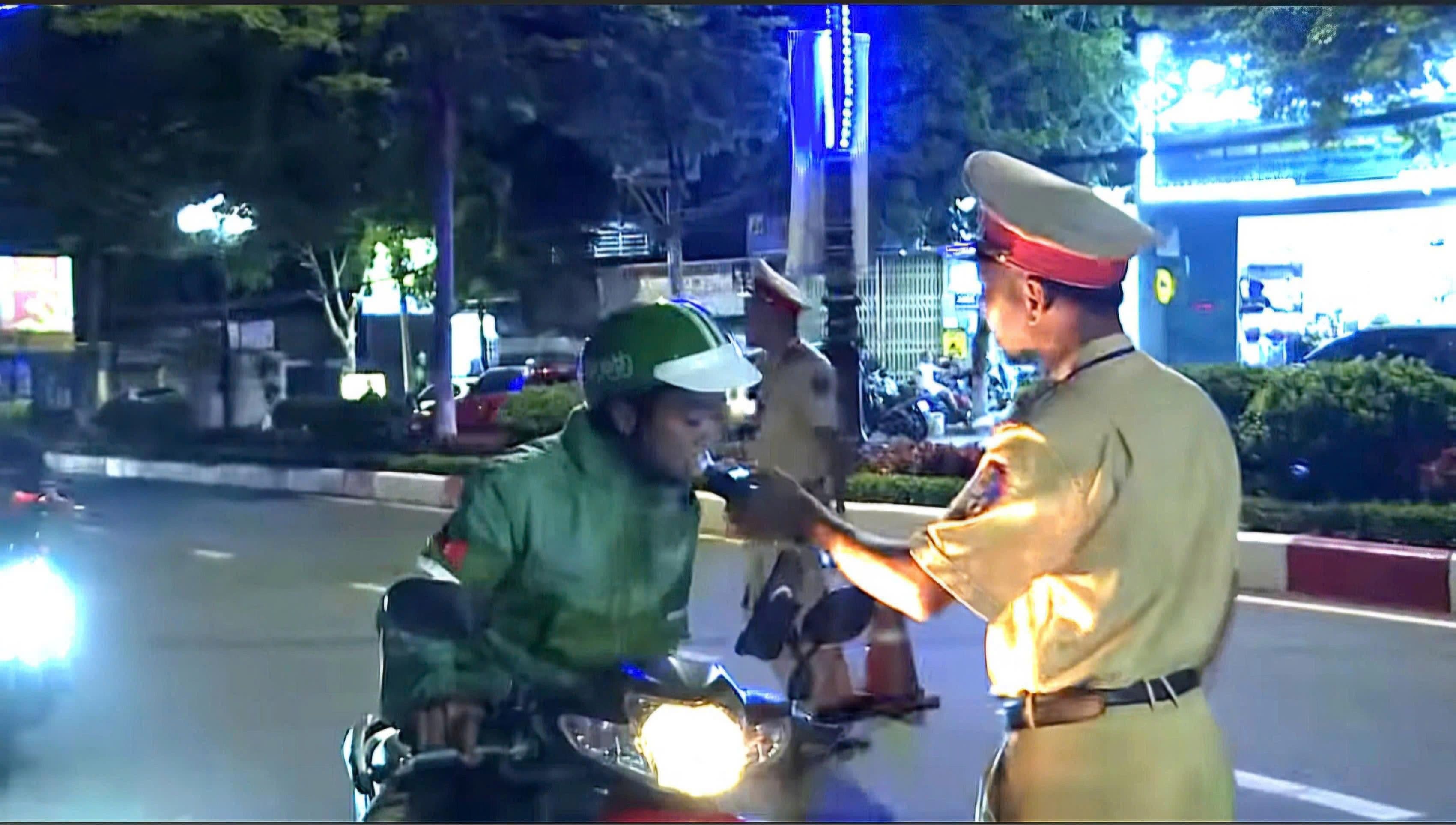 Cảnh sát giao thông kiểm tra nồng độ cồn của người điều khiển xe máy vào ban đêm
