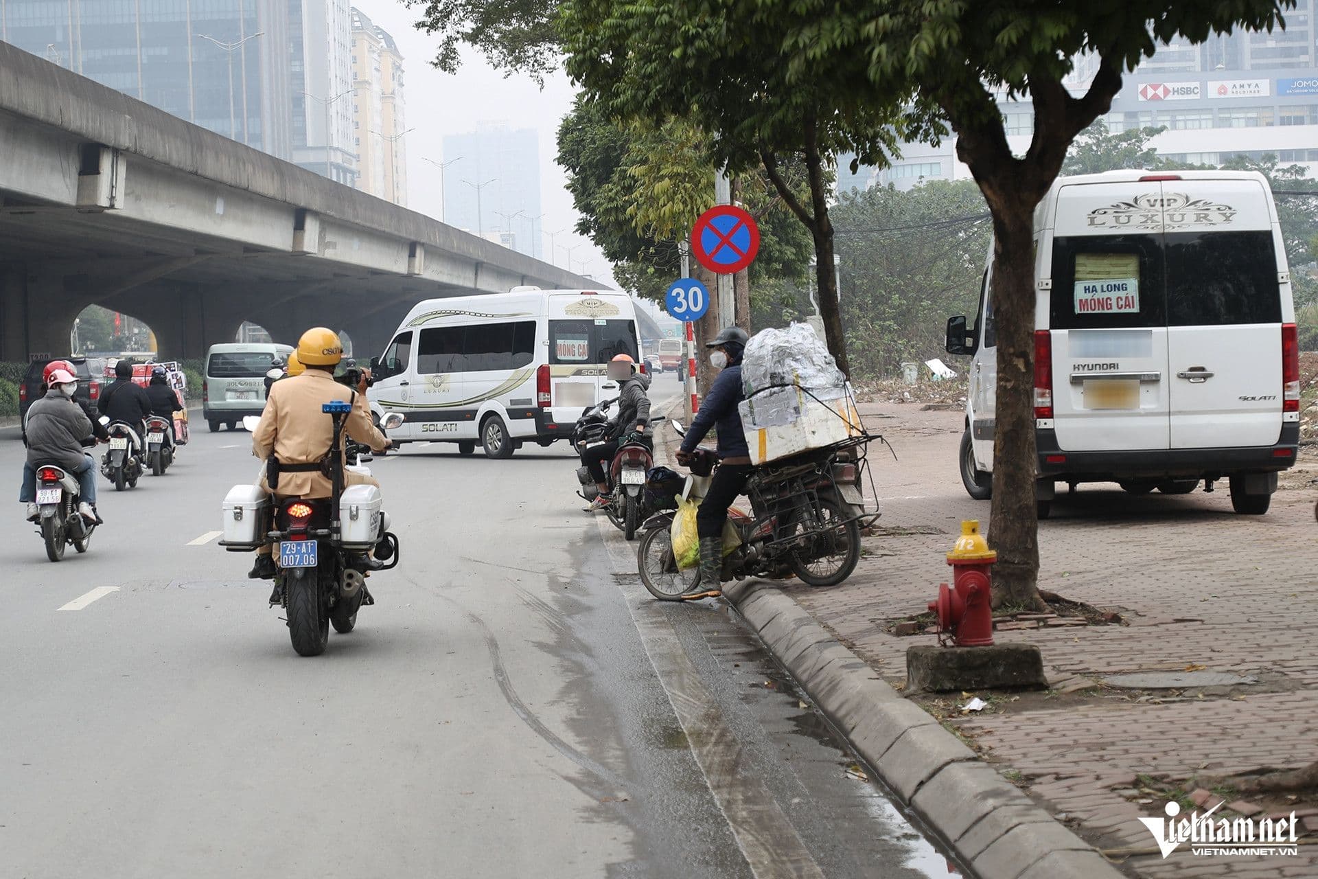 Cảnh sát giao thông tuần tra trên đường, phía sau là các phương tiện giao thông và xe khách, minh họa công tác tuần tra và giám sát.