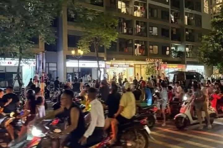 Cảnh sát và người dân tụ tập đông đúc trước sảnh chung cư nơi phát hiện thi thể nam thanh niên.