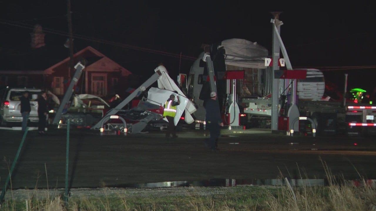 Cảnh tượng ban đêm tại một khu vực bị tàn phá với các phương tiện khẩn cấp và người dân đang làm việc, thể hiện nỗ lực cộng đồng trong việc ứng phó và tái thiết.