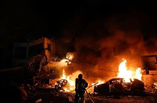 Cảnh tượng cháy nổ và đổ nát vào ban đêm, minh họa những biến động và xung đột địa chính trị mà Việt Nam phải đối mặt trong điều hành giá xăng dầu.