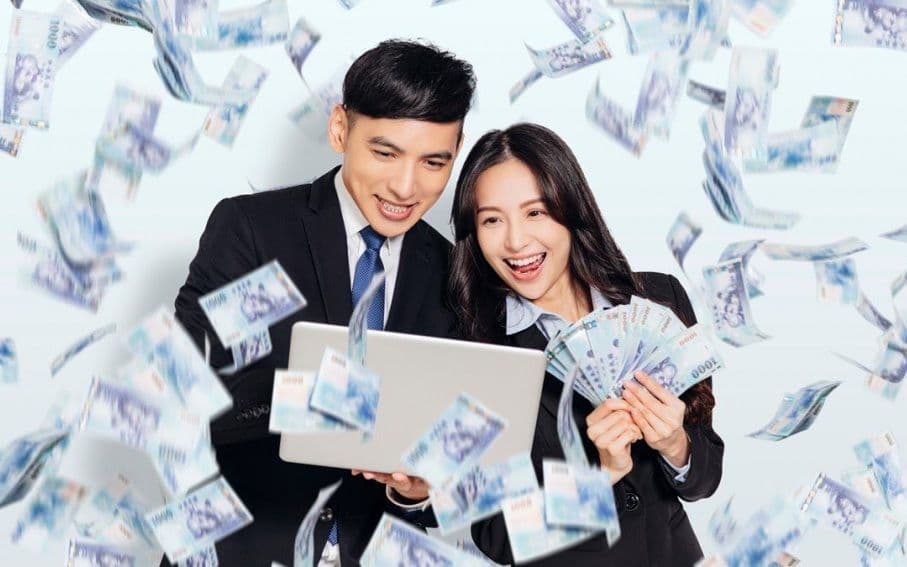 Cặp đôi vui vẻ nhìn vào máy tính xách tay với tiền bay xung quanh, minh họa tử vi là công cụ hỗ trợ quản lý tài chính và kiến tạo cuộc sống thành công.