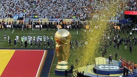 Cúp vàng World Cup trên bục vinh quang với pháo hoa giấy và khán giả reo hò, biểu tượng cho giải đấu bóng đá toàn cầu.