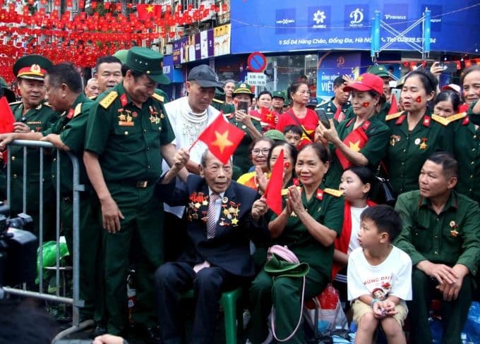 Cựu chiến binh với lá cờ Tổ quốc, tự hào tham dự lễ kỷ niệm Quốc khánh, biểu tượng của di sản và tinh thần dân tộc.