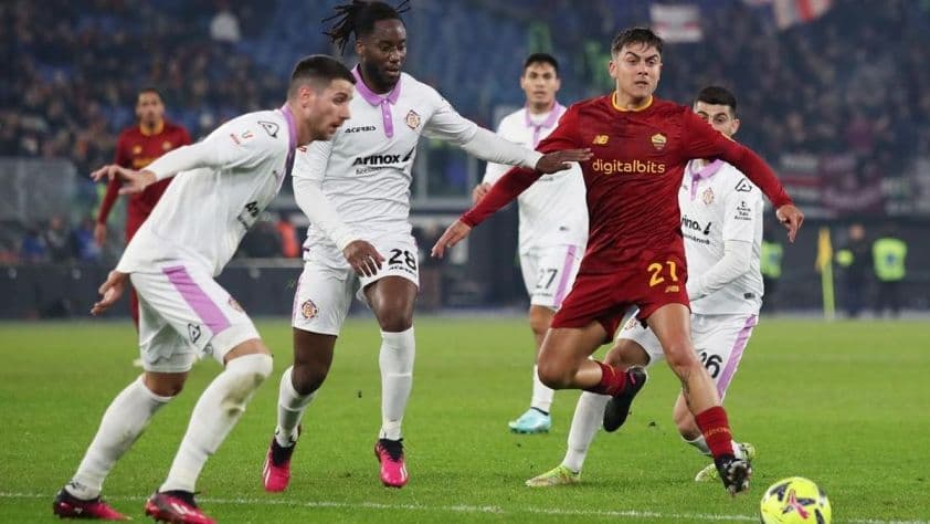 Cầu thủ AS Roma (áo đỏ) tranh bóng với cầu thủ Cremonese (áo trắng) trên sân cỏ