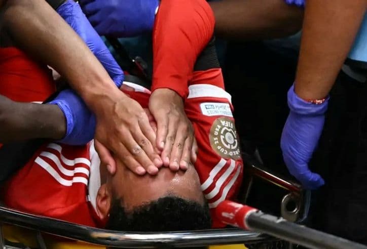 Cầu thủ bóng đá bị chấn thương trên sân, thể hiện gánh nặng thể lực.