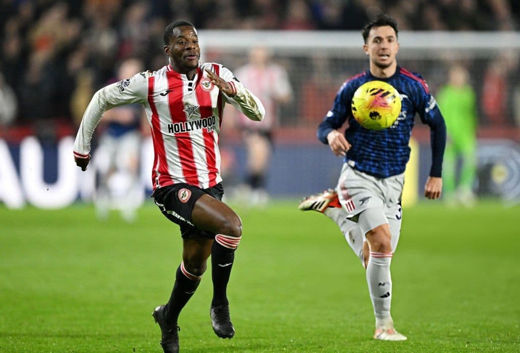 Cầu thủ Brentford bứt tốc, tượng trưng cho cuộc đua căng thẳng và áp lực mà Arsenal đang đối mặt.