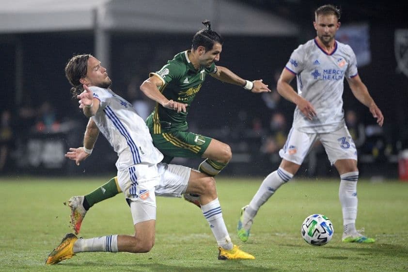 Cầu thủ FC Cincinnati (áo trắng xanh) tranh chấp bóng với cầu thủ Portland Timbers (áo xanh vàng) trong trận đấu MLS.