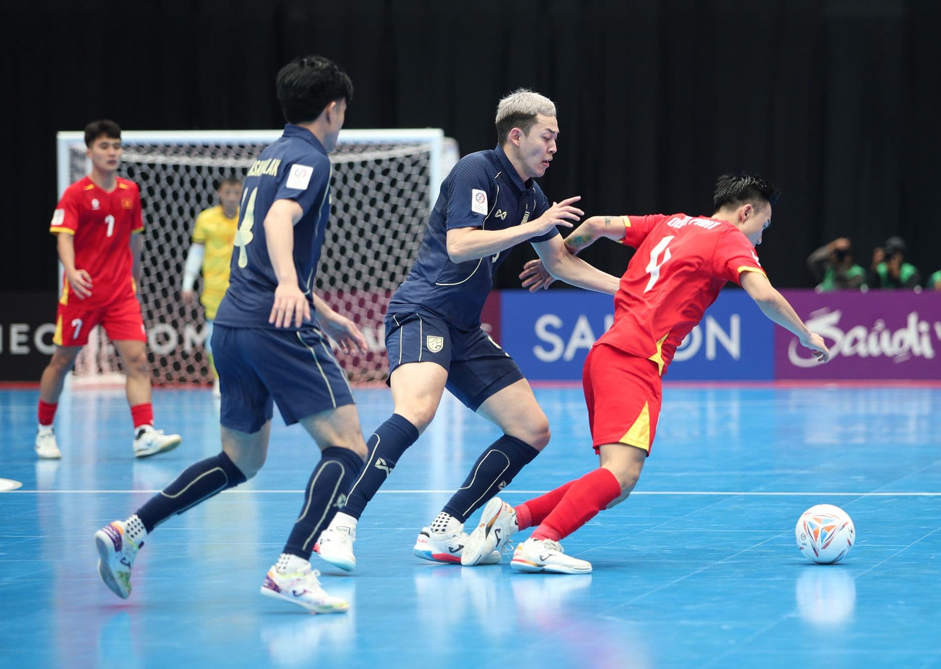 Cầu thủ futsal Việt Nam số 4 dẫn bóng vượt qua hai cầu thủ Thái Lan trong trận đấu