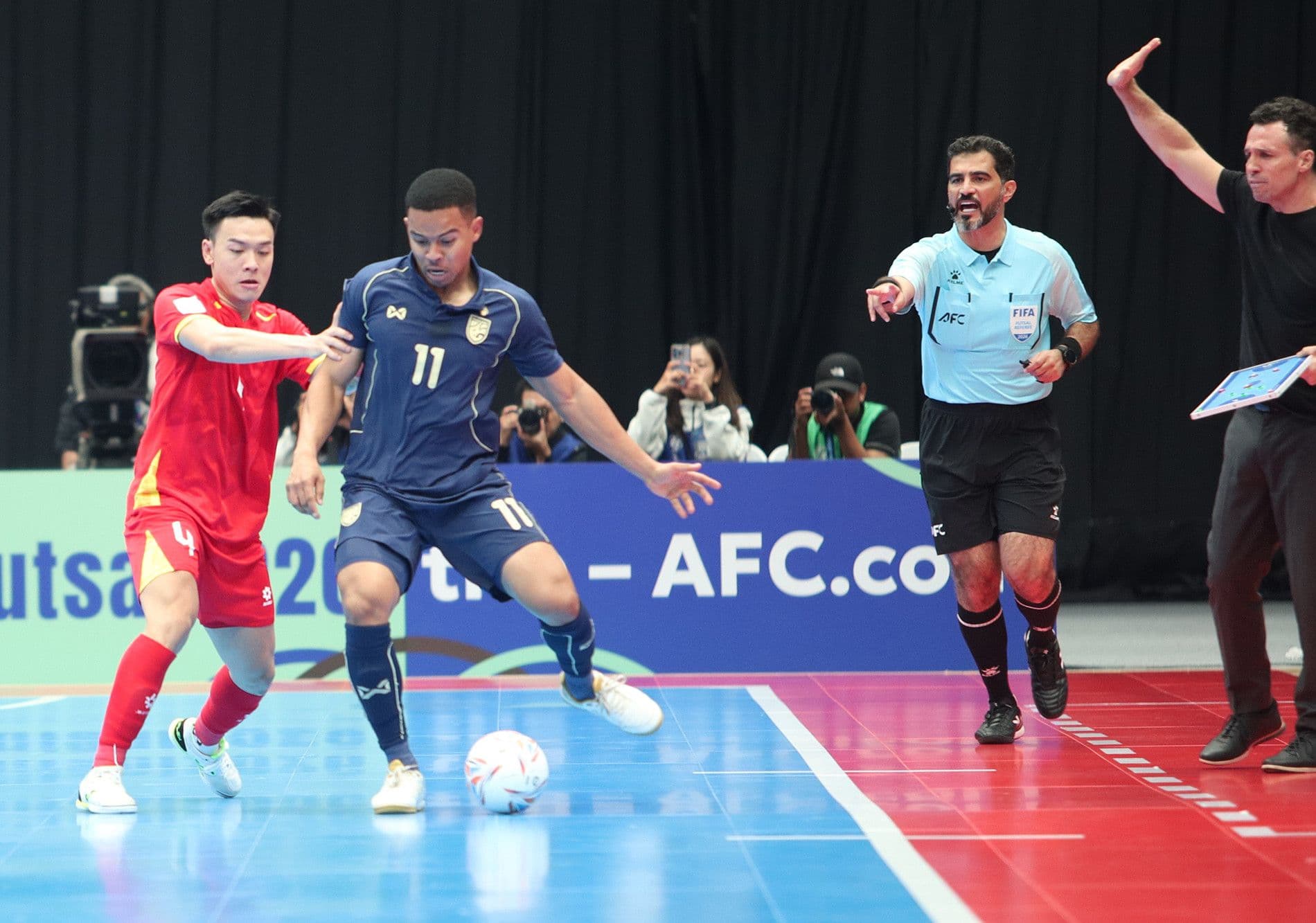 Cầu thủ futsal Việt Nam số 4 và cầu thủ Thái Lan số 11 tranh chấp bóng dưới sự giám sát của trọng tài