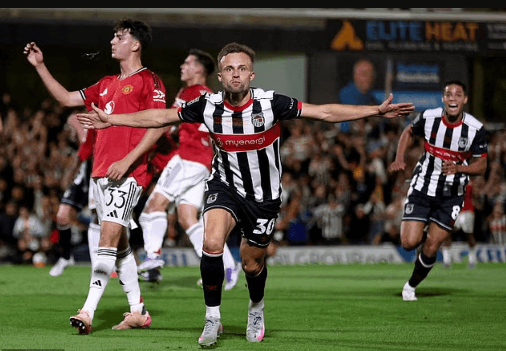 Cầu thủ Grimsby Town ăn mừng bàn thắng trong khi các cầu thủ MU thất vọng