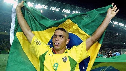 Cầu thủ huyền thoại Ronaldo của Brazil giơ cao lá cờ quốc gia, biểu tượng của một nhạc trưởng tài năng trong thế hệ vàng.