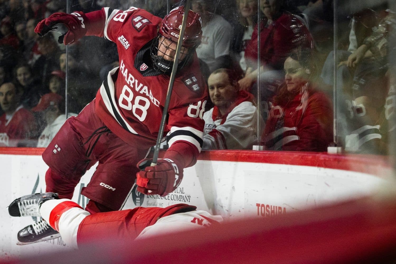 Cầu thủ khúc côn cầu Harvard va chạm với đối thủ, tượng trưng cho những thách thức mà trường đang đối mặt.