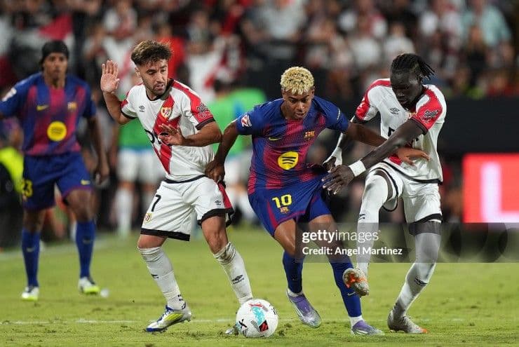 Cầu thủ Lamine Yamal của Barcelona tranh bóng với hai cầu thủ Rayo Vallecano trong trận đấu.
