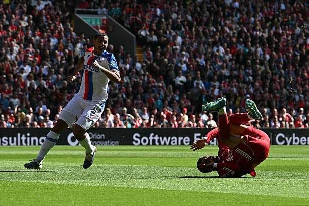 Cầu thủ Liverpool ngã trên sân khi đối đầu Crystal Palace, tượng trưng cho 'ám ảnh' và 'lời nguyền' trong các trận đấu.