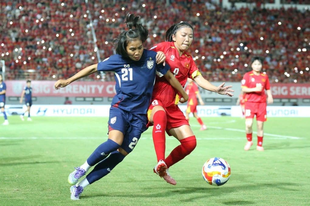 Cầu thủ nữ Việt Nam và Thái Lan tranh chấp bóng quyết liệt trên sân cỏ, thể hiện sự đối đầu căng thẳng.