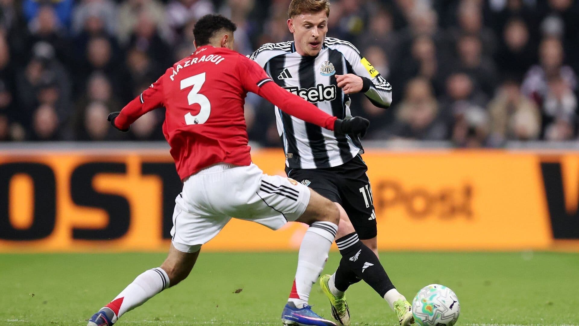 Cầu thủ Newcastle United nỗ lực tranh chấp bóng với cầu thủ Manchester United, thể hiện bản lĩnh và ý chí chiến thắng.