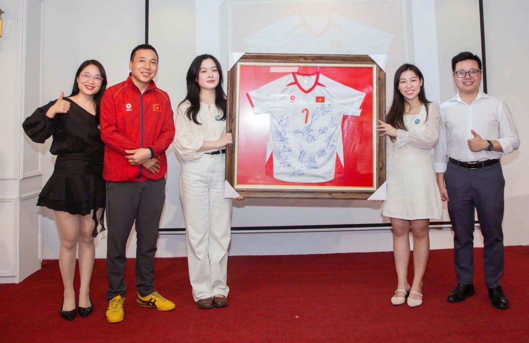 Cầu thủ Đình Bắc cùng nhóm người hâm mộ bên chiếc áo đấu có chữ ký, thể hiện sự kết nối chân thật với công chúng.