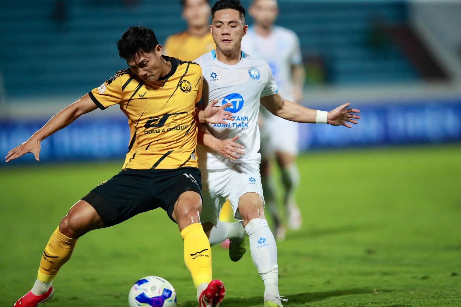 Cầu thủ Thép Xanh Nam Định (áo trắng) tranh chấp bóng quyết liệt với cầu thủ Đông Á Thanh Hóa (áo vàng) trên sân Thiên Trường.