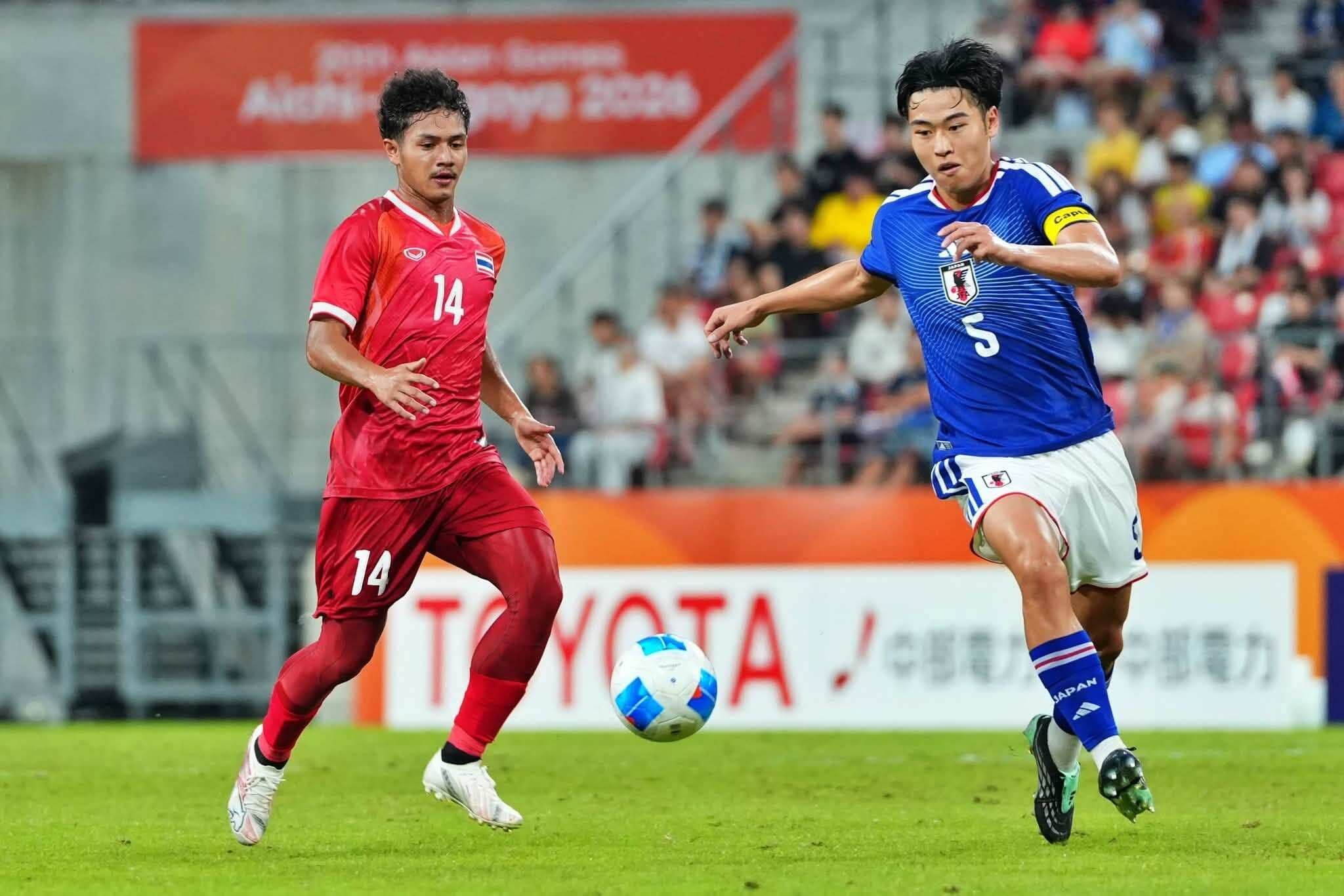 Cầu thủ U23 Nhật Bản đi bóng vượt qua sự truy cản của cầu thủ U23 Thái Lan