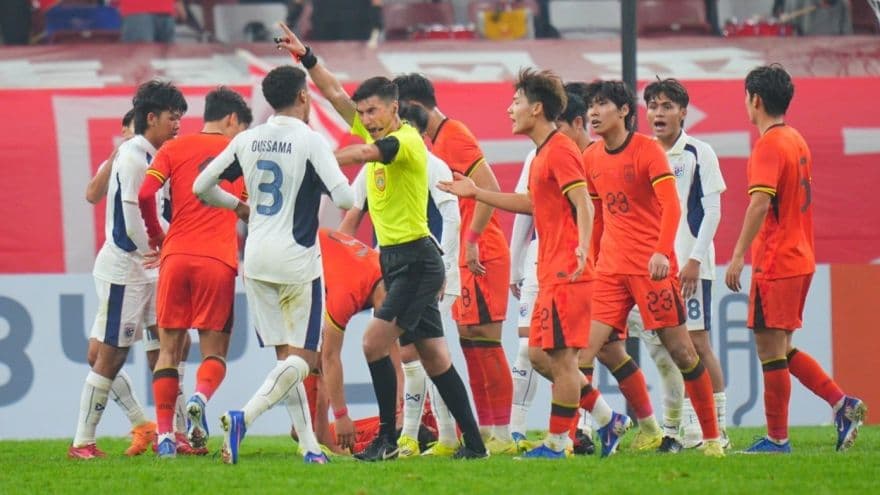 Cầu thủ và trọng tài trong tình huống căng thẳng trên sân, thể hiện áp lực trận đấu