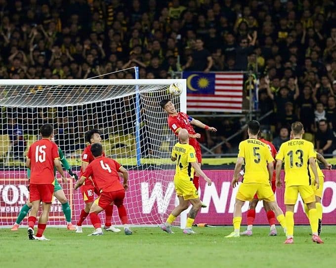 Cầu thủ Việt Nam (áo đỏ) và Malaysia (áo vàng) tranh bóng trong trận đấu vòng loại Asian Cup 2027, nơi Việt Nam thua 0-4.