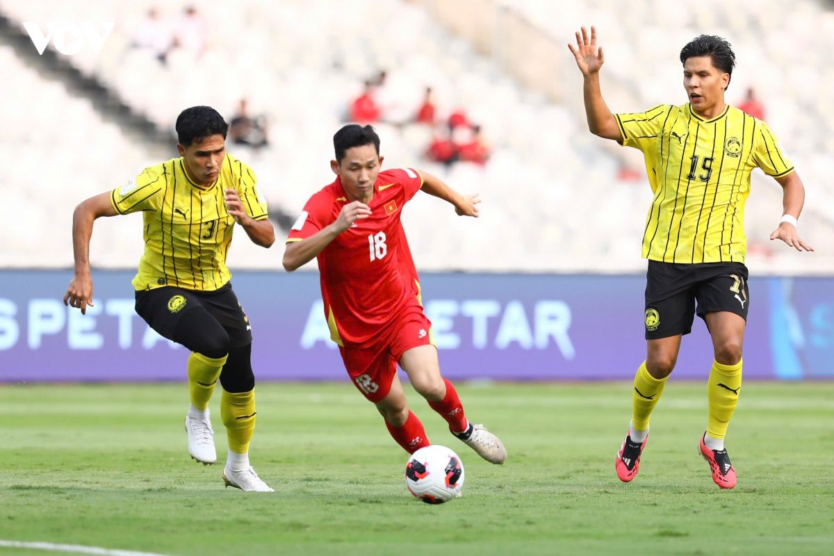 Cầu thủ Việt Nam số 18 Hoàng Đức rê bóng vượt qua hai cầu thủ Malaysia trong trận đấu FIFA ASEAN Cup 2026.