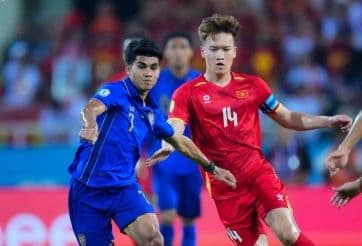 Cầu thủ Việt Nam và Thái Lan tranh chấp bóng trên sân, tượng trưng cho sự cạnh tranh khu vực và phản ứng của người hâm mộ đối với chính sách nhập tịch.