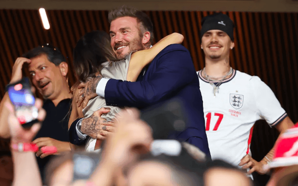 David Beckham ôm Victoria Beckham với nụ cười rạng rỡ, thể hiện sự thấu hiểu và tình cảm sâu sắc của họ.