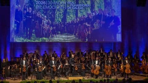Dàn nhạc giao hưởng Real Filharmonía de Galicia biểu diễn trên sân khấu, phía sau là màn hình chiếu hình ảnh các nhạc công trong khung cảnh thiên nhiên.