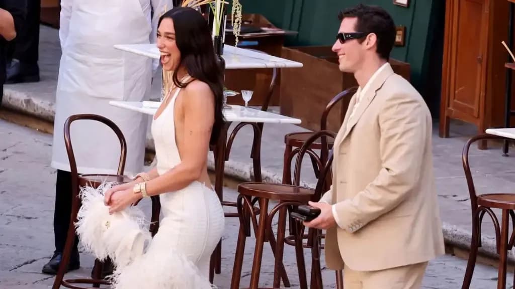 Dua Lipa và Callum Turner cười rạng rỡ trong trang phục lễ cưới tại một buổi lễ ngoài trời