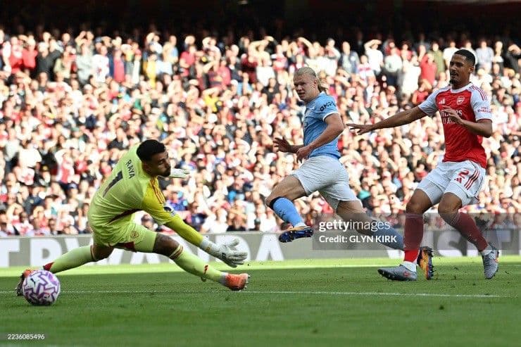 Erling Haaland của Manchester City ghi bàn vào lưới thủ môn Raya của Arsenal, thể hiện sức mạnh tấn công phủ đầu.