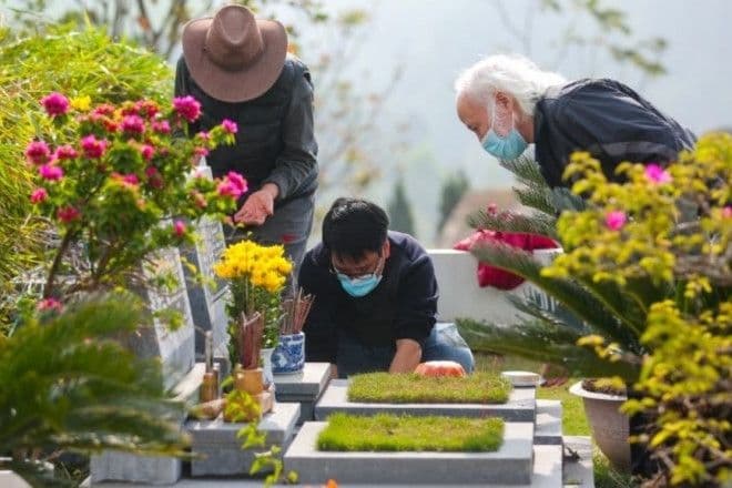 Gia đình cùng nhau dọn dẹp, đặt hoa và thắp hương tại mộ phần trong tiết Thanh Minh.