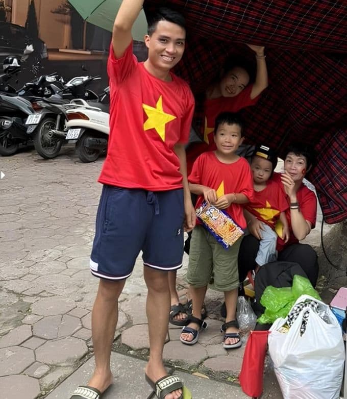 Gia đình Hà My mặc áo cờ đỏ sao vàng, căng bạt trú mưa tại ngã tư Phan Đình Phùng, thể hiện sự háo hức chờ đợi diễu binh.