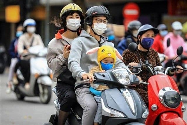 Gia đình đi xe máy mặc áo ấm và khẩu trang trong không khí se lạnh đầu mùa ở miền Bắc Việt Nam.