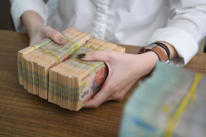 Giao dịch tiền mặt tại ngân hàng, minh họa cho thu nhập vãng lai và ngưỡng khấu trừ thuế
