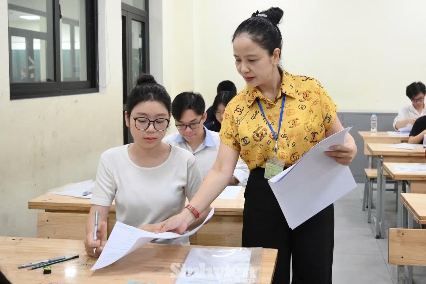 Giáo viên hướng dẫn học sinh trong giờ kiểm tra, minh họa việc triển khai chính sách giáo dục mới.