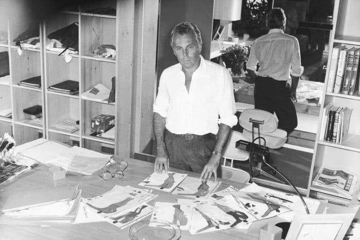 Giorgio Armani đứng giữa các bản phác thảo, thể hiện vai trò kiến trúc sư định hình phong cách toàn cầu.