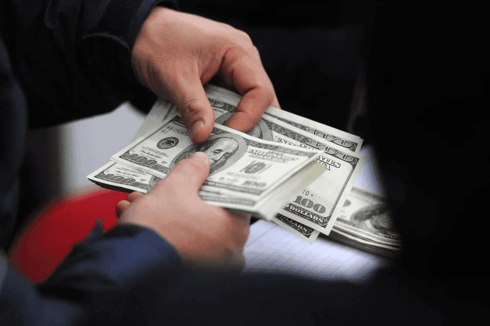 Hai bàn tay đang trao đổi những tờ tiền đô la Mỹ, minh họa cho hoạt động giao dịch USD trên thị trường tự do và ngân hàng.