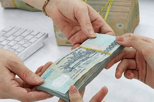 Hai bàn tay đang trao đổi tiền mặt, tượng trưng cho việc nhận lương hưu hoặc trợ cấp xã hội, nhấn mạnh khía cạnh tài chính của tuổi già.