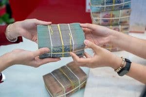 Hai bàn tay trao đổi các cọc tiền, tượng trưng cho các giao dịch tài chính bị che giấu hoặc không minh bạch.