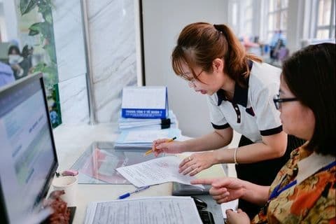 Hai cán bộ công chức đang trao đổi công việc, thể hiện sự hợp tác và đổi mới trong quy trình hành chính.