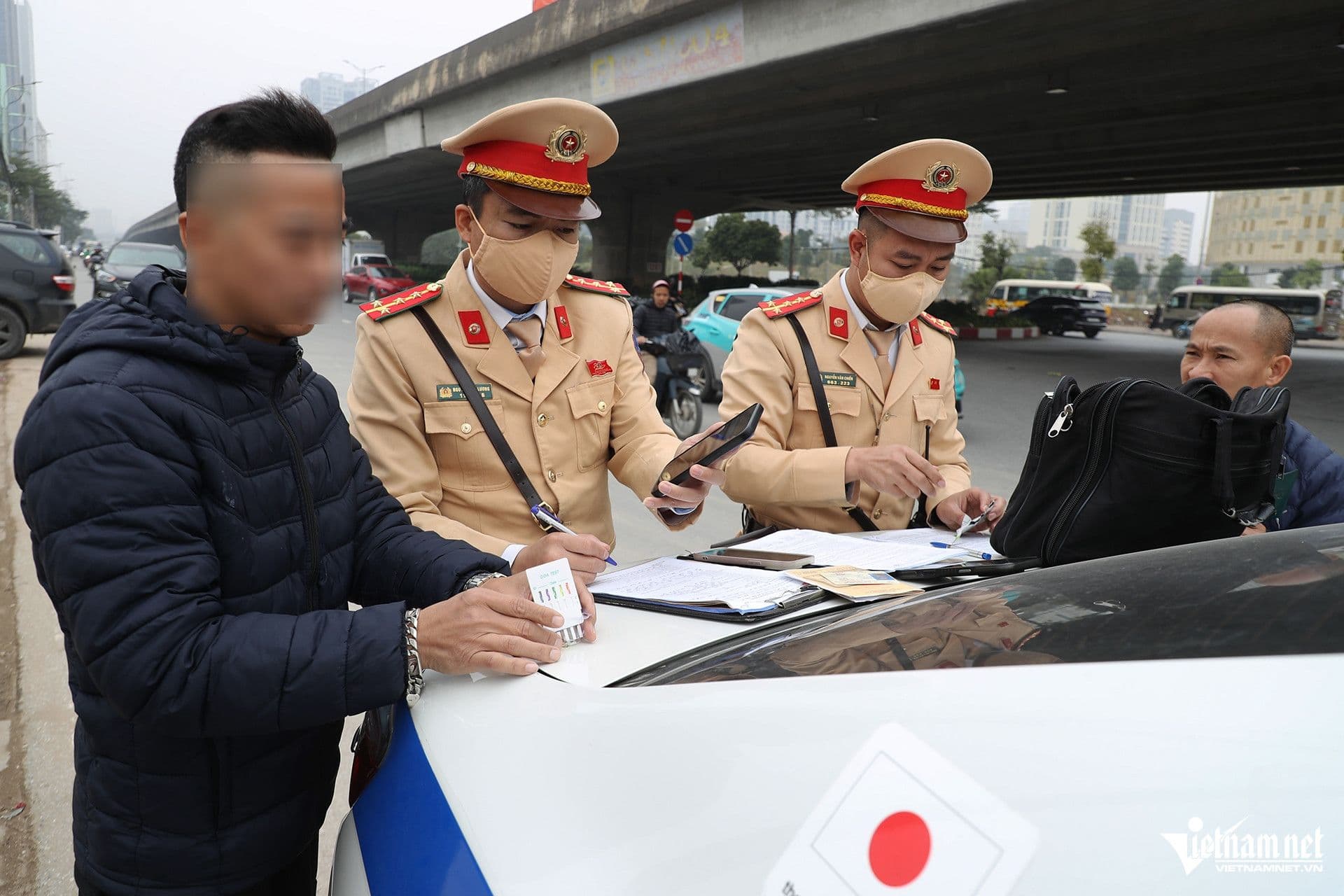 Hai cảnh sát giao thông tương tác với người dân bên cạnh xe cảnh sát, một người đang sử dụng điện thoại, thể hiện sự kết hợp giữa công nghệ và yếu tố con người trong quản lý giao thông.