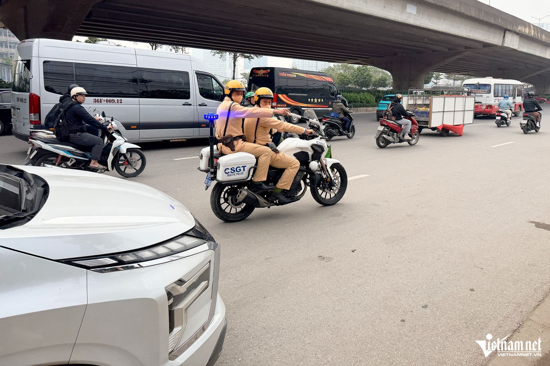 Hai cảnh sát giao thông trên mô tô tuần tra trên đường phố đông đúc dưới cầu vượt, thể hiện sự hiện diện và kiểm soát giao thông của CSGT.