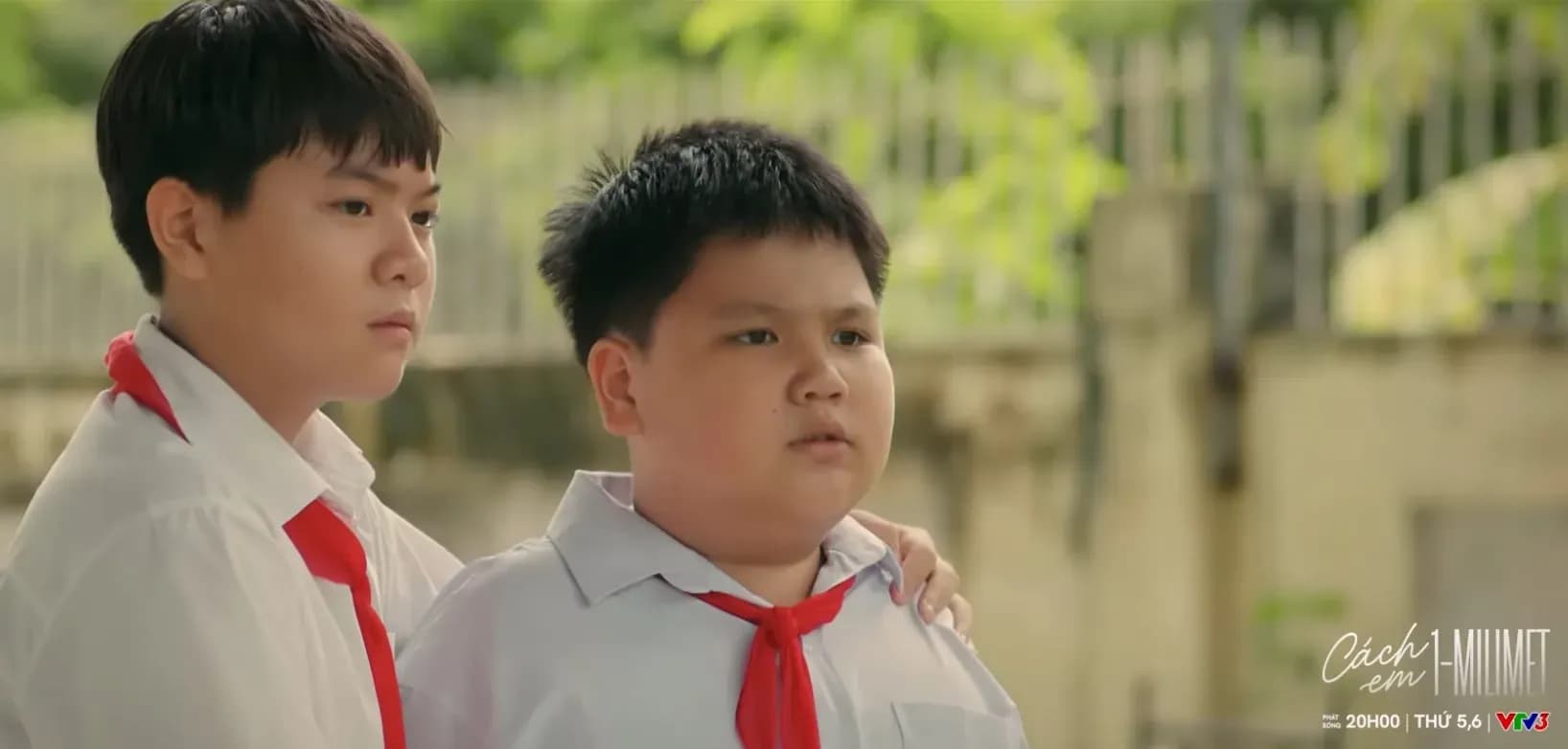 Hai cậu bé học sinh trong đồng phục, một người đặt tay lên vai người kia, với logo VTV3 và tên phim 'Cách em 1 milimet' thể hiện chủ đề phim gia đình hiện đại.