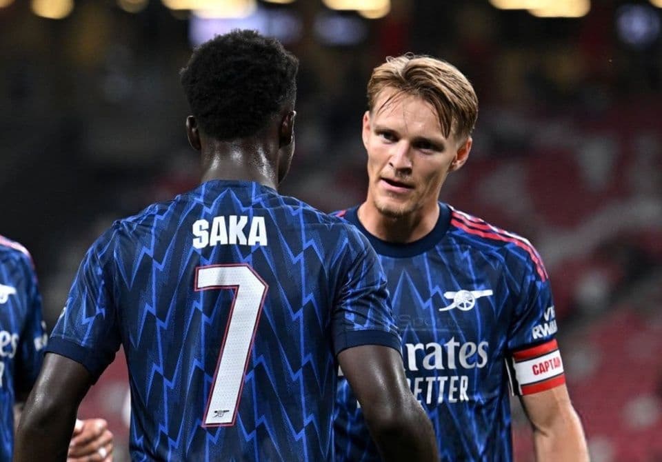 Hai cầu thủ Arsenal Saka và Odegaard trao đổi trên sân.