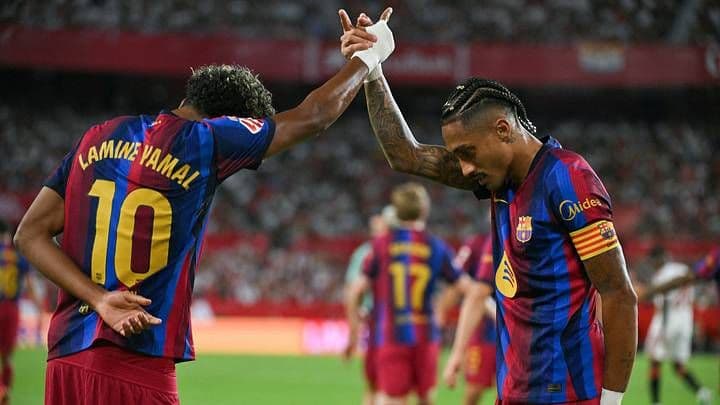 Hai cầu thủ Barcelona Lamine Yamal và Raphinha ăn mừng chiến thắng trên sân cỏ, thể hiện tinh thần đồng đội.