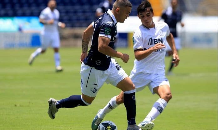 Hai cầu thủ bóng đá tranh chấp bóng trên sân, thể hiện sự cạnh tranh trong trận đấu.